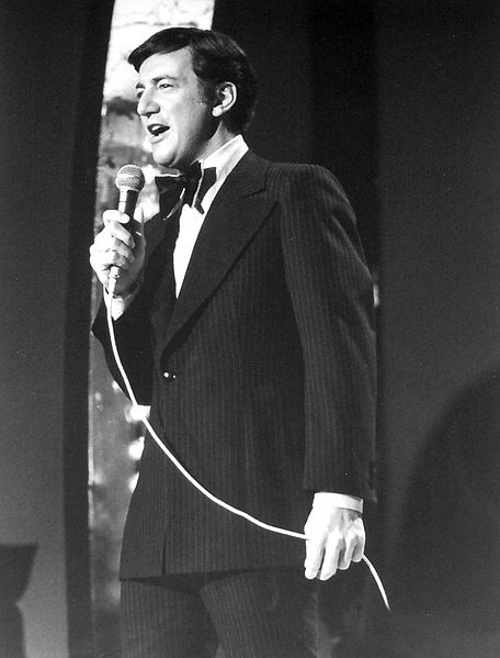 Bobby Darin singing into a microphone. Black and white. 