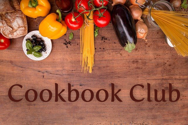 Ingredients are arranged on a wood table with the words 'Cookbook Club' below them. 