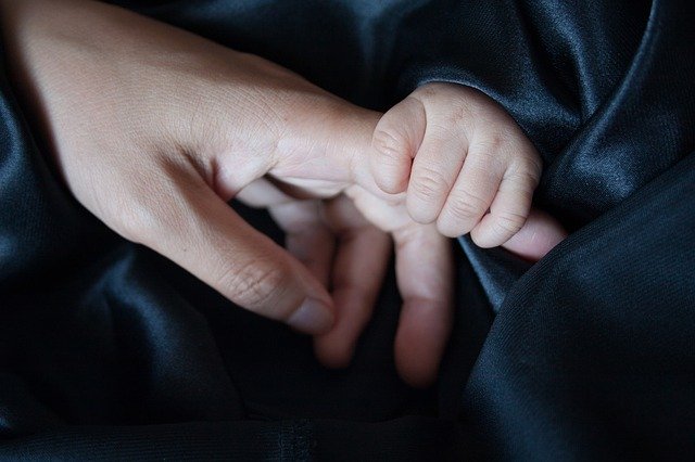 baby holding an adult's finger