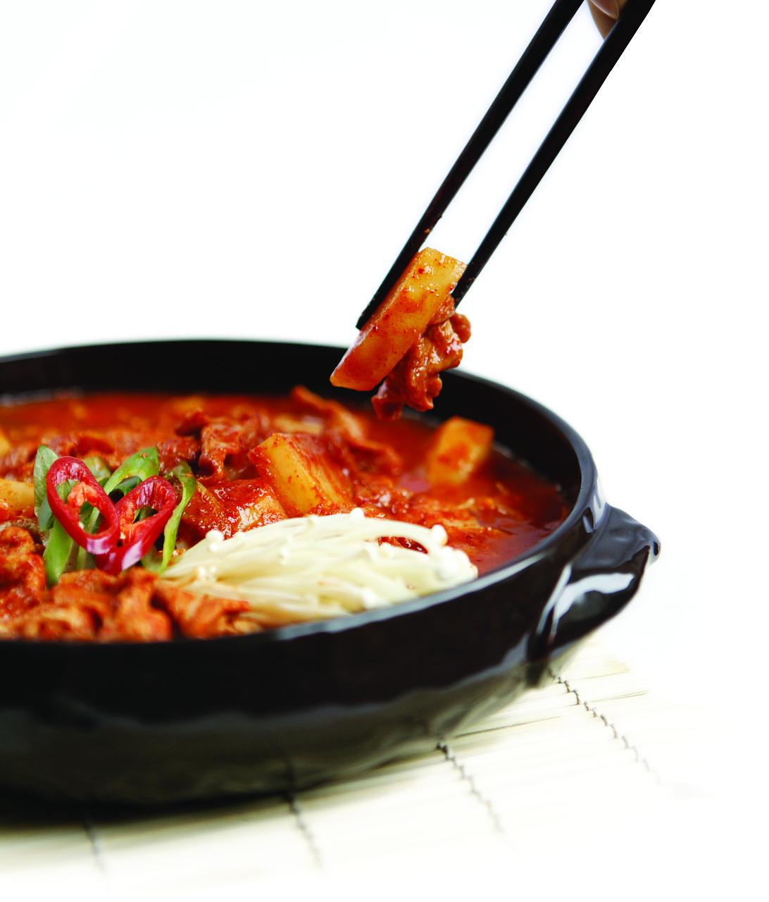 a bowl with kimchi and a pair of chopsticks removing one piece
