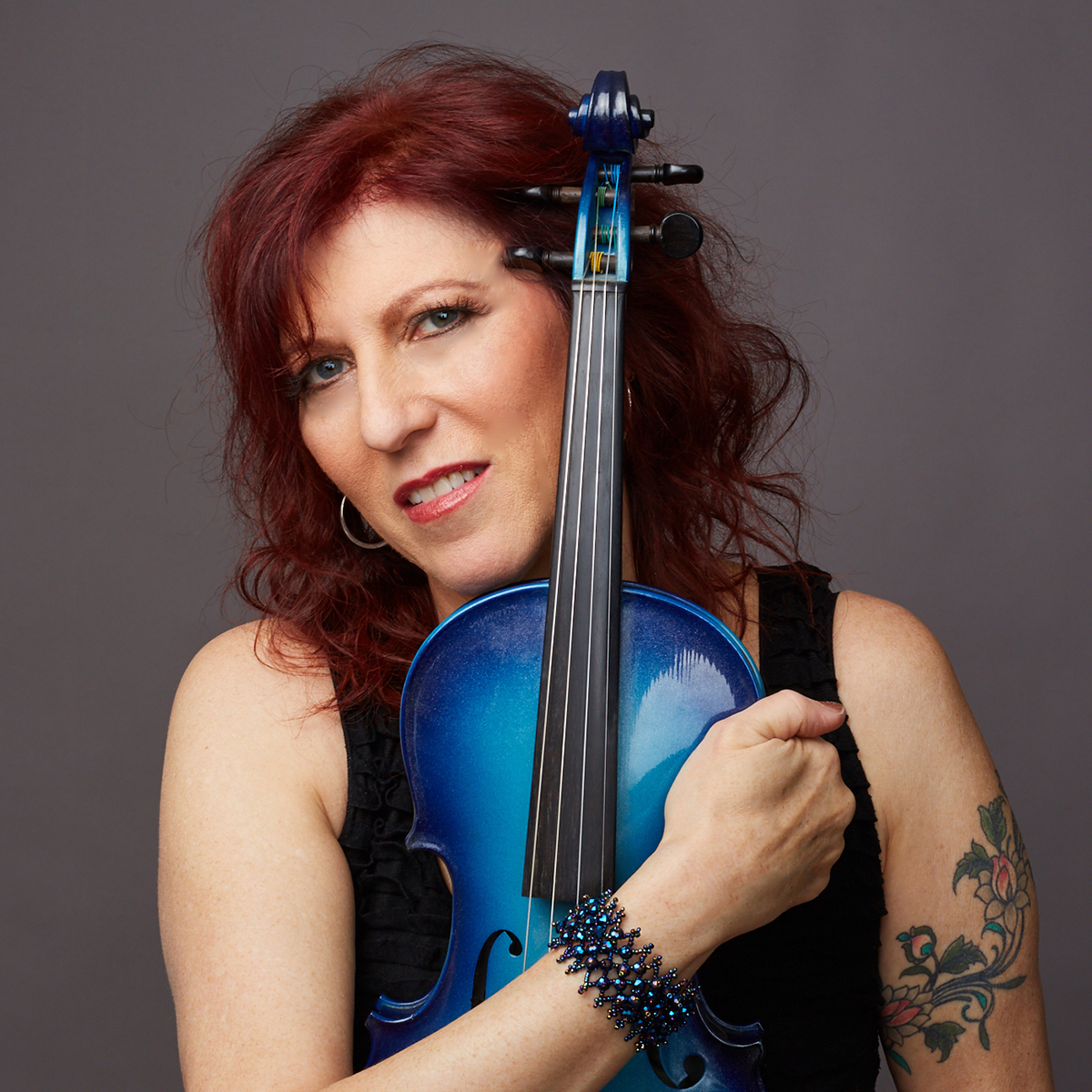 Deni Bonet with her arm around a blue violin 