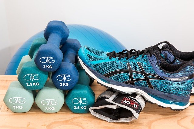 A sneaker leaning against some small free weights in front of a yoga mat 
