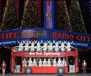 Rockettes posed on a sightseeing bus in front of radio city music hall