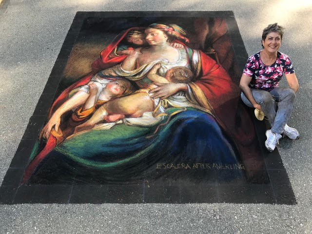 an artist poses with a chalk art painting that looks like a classical portrait