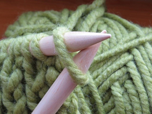 Two pink needles stuck through green yarn