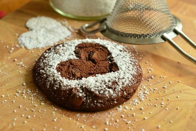 A brown cookie with powdered sugar shaped in a heart 