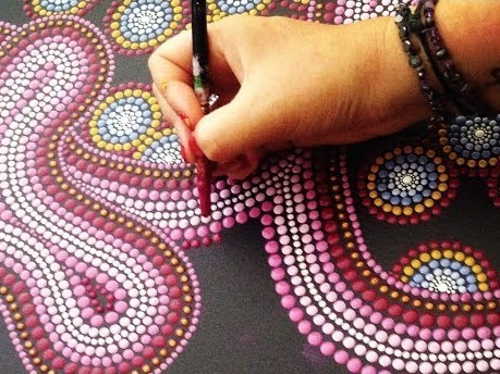 a hand adds a pink dot to a nearly completed red and pink dot picture of a snake