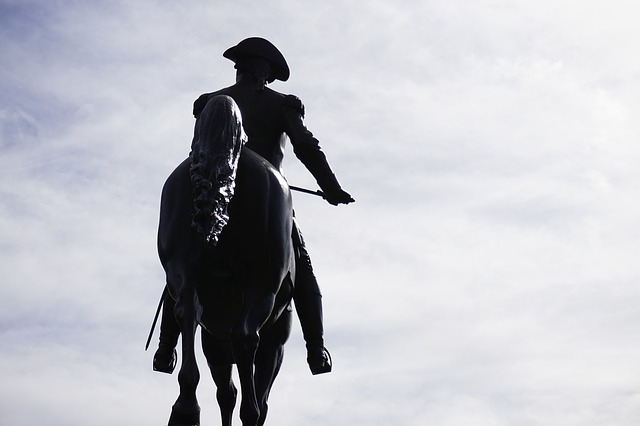 Statue of Paul Revere in silhouette against a cloudy sky
