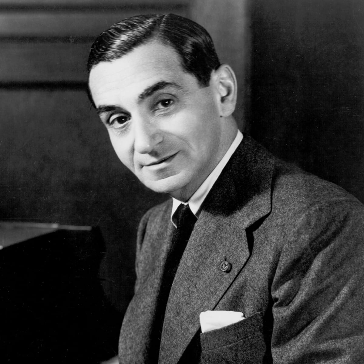 Black and white photo of a man (Irving Berlin) from the chest up,  he has a slicked back hairdo, and is smiling very slightly