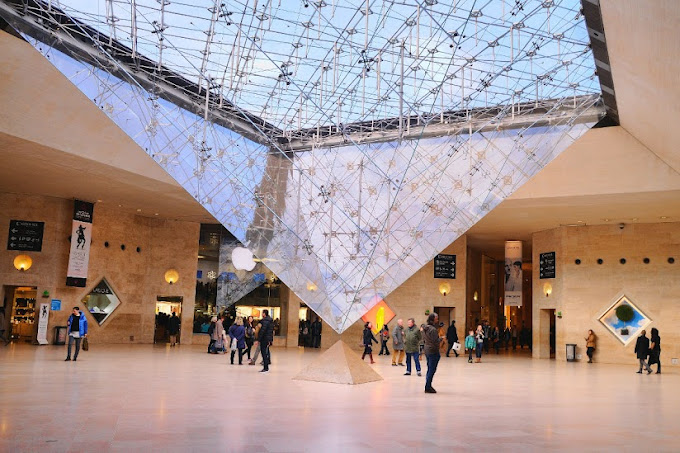 color photo of the vestibule of the Louvre with the glass pyramid dipping into the center 