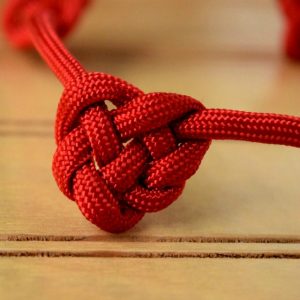 Red paracord tied in a Celtic knot that looks like a heart