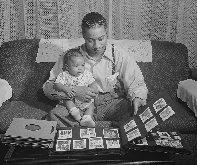 A man at a child sit and look through a scrapbook together
