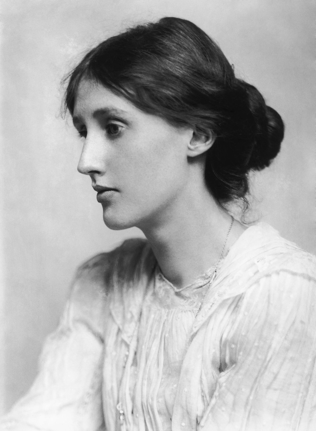 black and white photograph of a young Virginia Woolf in profile. Her hair is back and she wears a white gown. 