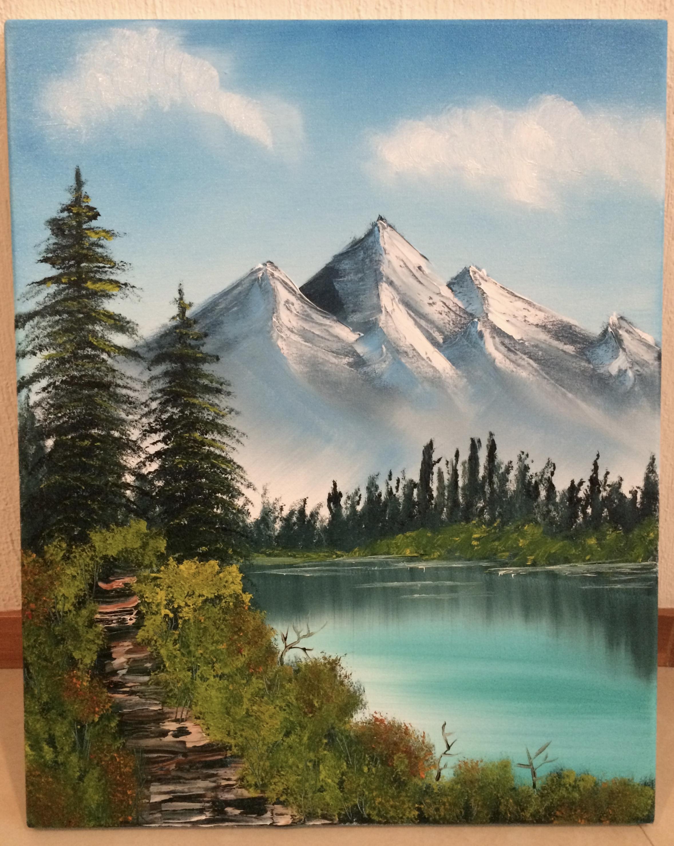 Bob Ross painting of mountains at a distance and pine trees at the fore. 