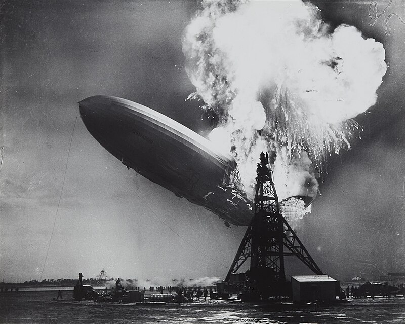 black and white photo of the Hindenburg crashing, flames towering in the air  
