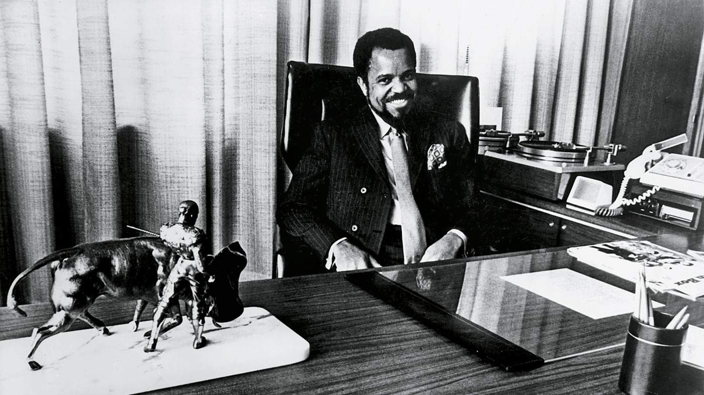 black and white photo of Berry Gordy sitting behind a desk 