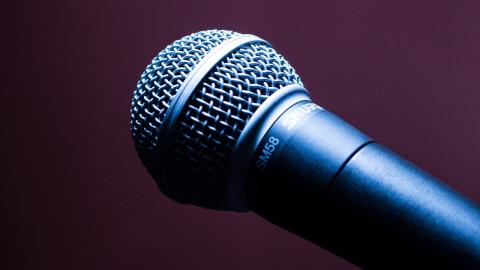 A microphone facing left against a dark background. 