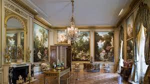 Color photo of a gallery room that looks like a 1800s era sitting room including a chandelier in the center