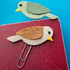 two felt birds with paperclip bottoms balanced on top of a red book