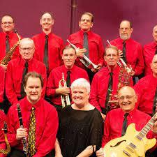 color picture of several band members in red, seated with their instruments around one woman in black