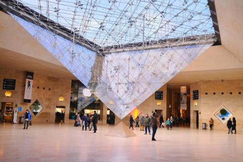 color photo of the vestibule of the Louvre with the glass pyramid dipping into the center 