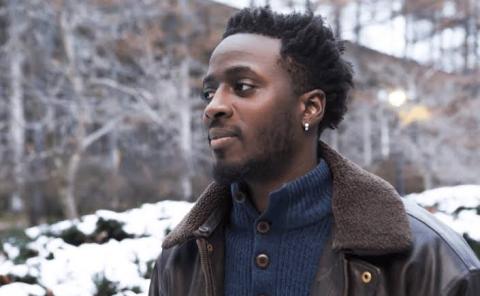 Color photo of Nana Kwame Adjei-Brenyah in profile, he appears to be walking outside on a cold day with snow in the background. 