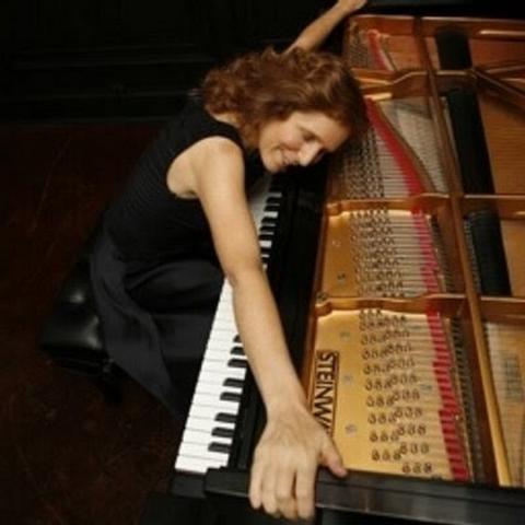 Pianist Carolyn Enger stretches her arms over her open piano 