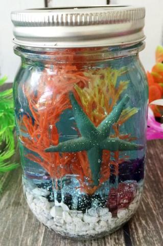 color photo of a mason jar with colorful rocks, plastic coral and a starfish