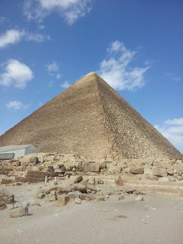 color photograph of a pyramid against a blue sky with few clouds 