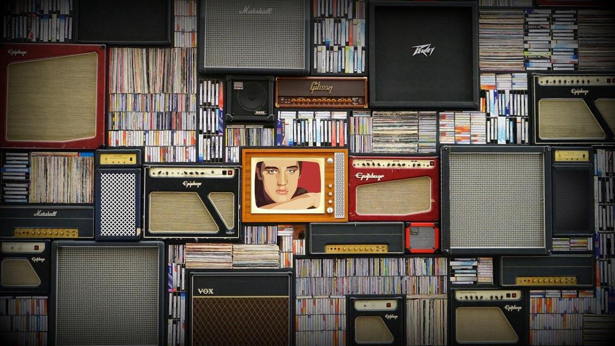 A tv with elvis presley on it, crammed in among many records