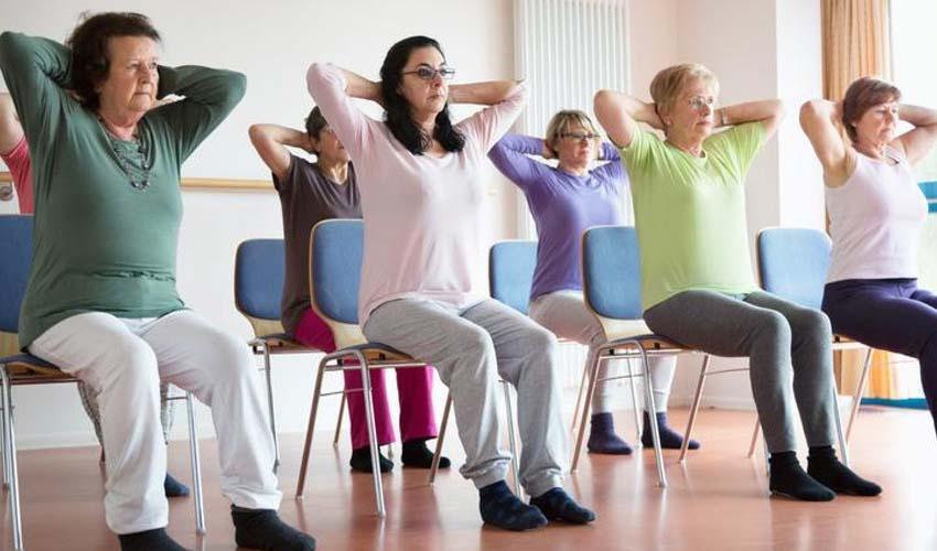 a group of adults sitting in chairs and stretching 