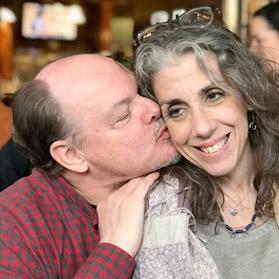 Color photo of the duo, Barry kissing his wife's cheek 