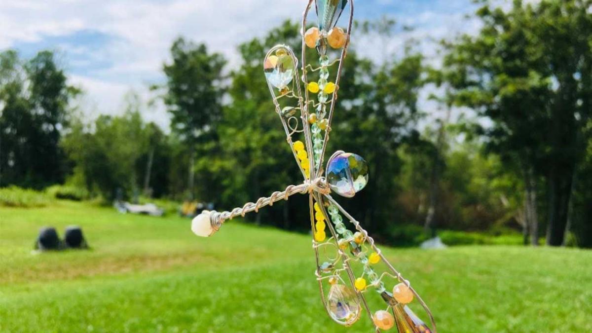 color photo of a whisk bent into the shape of a dragonfly and dotted with beads. 