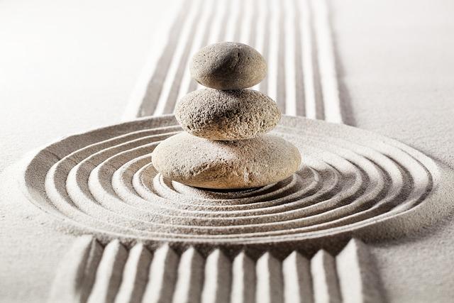 a color photograph of three stones piled by size in the center of raked sand 